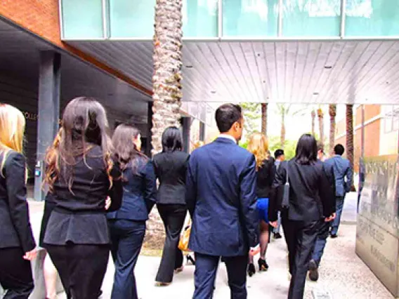 Future medical students in suits walking towards medical education building.