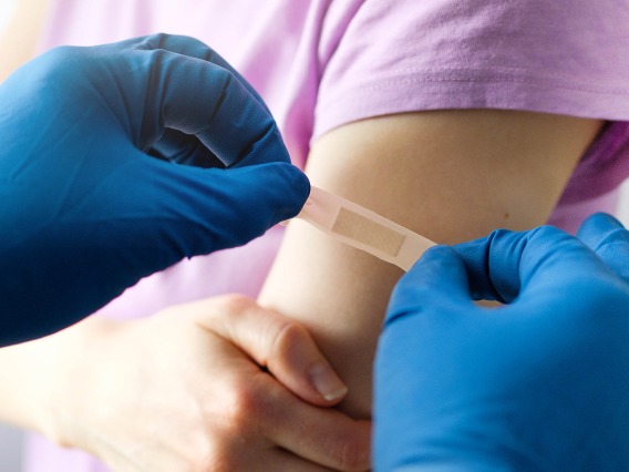 A doctor putting a band-aid on a persons' upper arm.