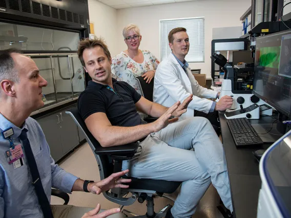 lab techs having a discussion around a computer screen