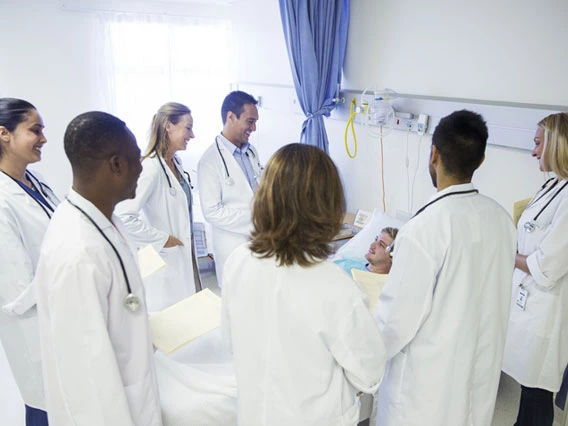 Photo of a group of doctors around patient in bed