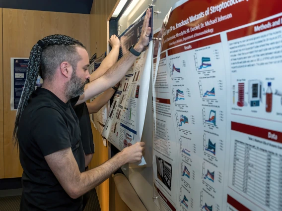 [Ivan Menendez Montes, PhD, a researcher in the lab of Cardiology chief and Sarver Heart Center director Hesham Sadek, MD, PhD, pins up his poster for display in the SOAR in the DOM Forum, April 24, at the BIO5 Institute.]