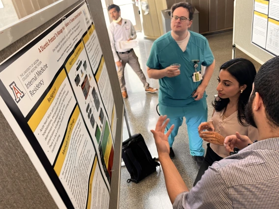 [Ryan Weyker, DO, a PGY-1 IM resident, looks at poster on diuretics while another resident discusses it with Swathi Somisetty, MD, also a PGY-1.]