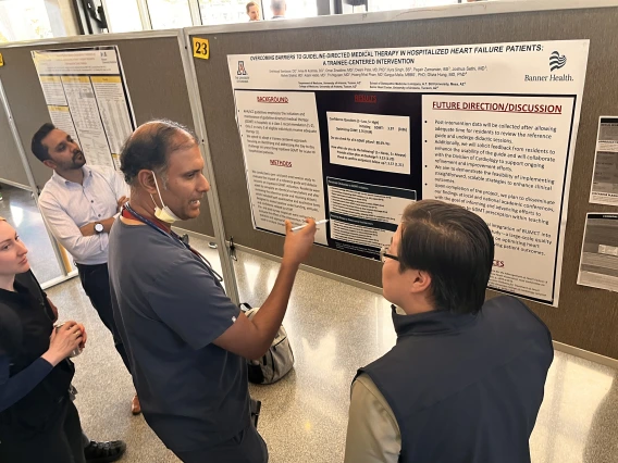 [Rajesh Kotagiri, MD, an Inpatient Medicine hospitalist and associate professor, asks questions of Enkhtsogt Sainbayar, DO, a PGY-2 IM resident, about his poster on “Overcoming Barriers to Guideline-Directed Medical Therapy in Hospitalized Heart Failure Patients: A Trainee-Centered Intervention.”]