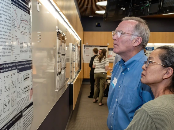 [Cardiology researchers Luke Szweda, PhD, and Patricia Szweda, MS, look at a poster at the SOAR in the DOM research forum.]