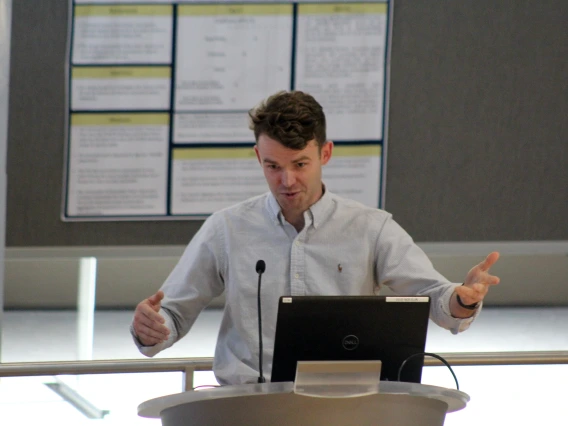 [PGY-2 Nathan Walton, MD, gestures as he talks about his research project, “Surety of Parasitosis: A curious case of Wohlfahrtiimonas Bacteremia,” during oral presentations.]