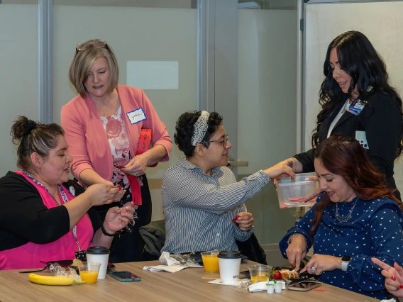 [Gastroenterology’s Carmen Mendoza and DOM facilities coordinator Isabel Goodson-Montelongo accept raffle tickets from Cynthia Campas and Dominica Padilla at the 2025 DOM Administrative Professionals Day breakfast. Prizes were distributed later.]