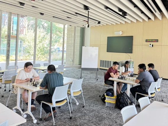 [Inaugural WellDOM Chess Club meeting participants lock in on moves they’d like to make: (table on left) Steve Sainbayar, DO (PGY-3 IM resident) and Nephrology’s Bijin Thajudeen, MD; (table on right) Asael Nuñez, MD (PGY-2 IM resident – in maroon top), Inpatient Medicine’s Anil Potharaju, MD, and Nathan Holt, DO (PGY-1 radiology resident – in black top), and his wife.]