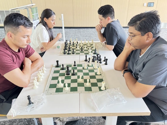 [Pondering a plan of attack or defense: Asael Nuñez, MD (PGY-2 IM resident – in maroon top), Inpatient Medicine’s Anil Potharaju, MD, and Nathan Holt, DO (PGY-1 radiology resident – in black top), and his wife.]