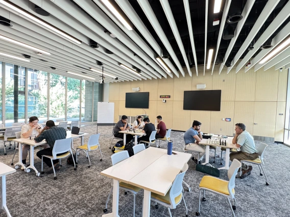 [At each table, chess players chat with each other about moves they’re making learning from more experienced players in the process and finding out more about them, their backgrounds and what sparked their interest in “the king’s game.”]