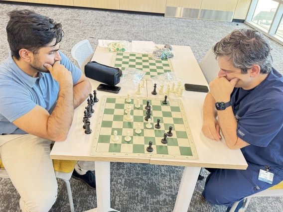 [The Division of Cardiology’s Talal Moukabary, MD (right), and Class of 2026 COM-T medical student Rohan Mittal give hard thought to each other’s next play as their match progresses: “I really appreciate all the work done to make this happen. I hope we make it a monthly event,” Dr. Moukabary said.]