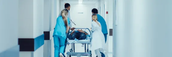 Emergency medicine professionals move a patient down a hallway on a gurney