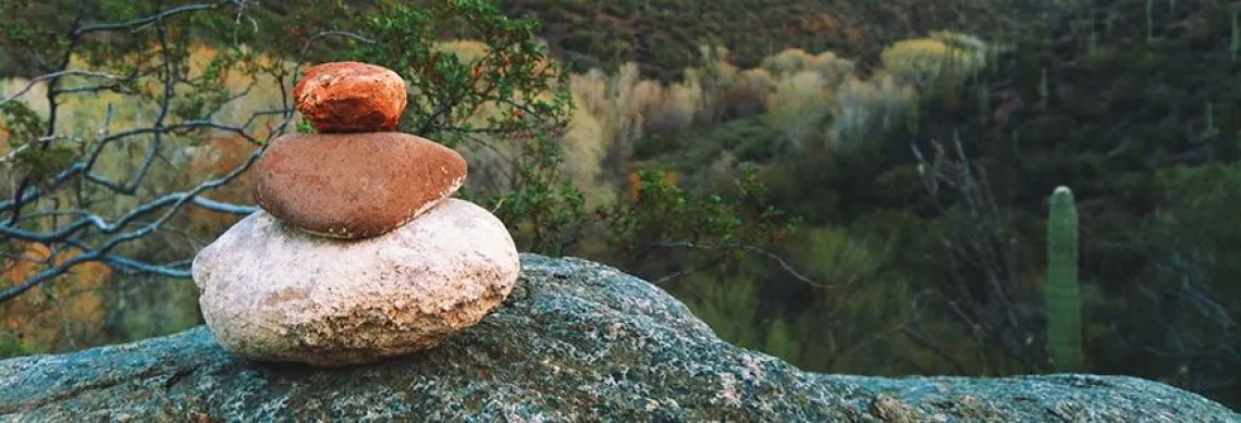 Photo of 3 river rocks balanced on a boulder