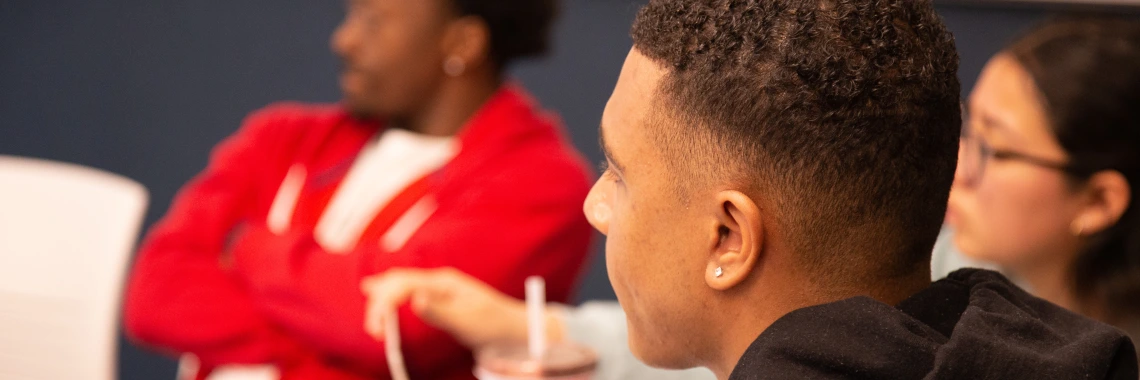 A diverse group of individuals seated in a classroom, engaged in learning and discussion.