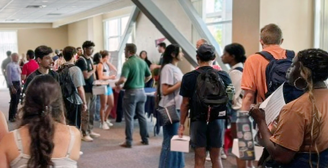 A diverse group of individuals gathered in a hallway, engaged in conversation and interaction.