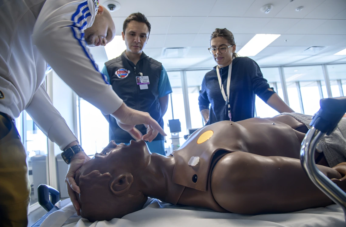 A man examines a mannequin in a medical simulation lab, highlighting hands-on training in healthcare education.