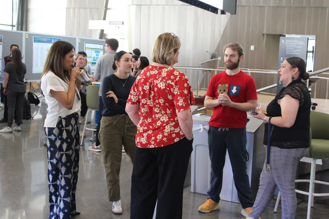[Two residents speak with IM Residency – Tucson program manager Mary Gosciminski (center in red top), admin Yuvia Anaya (left) and former coordinator Monica Jimenez (right).]