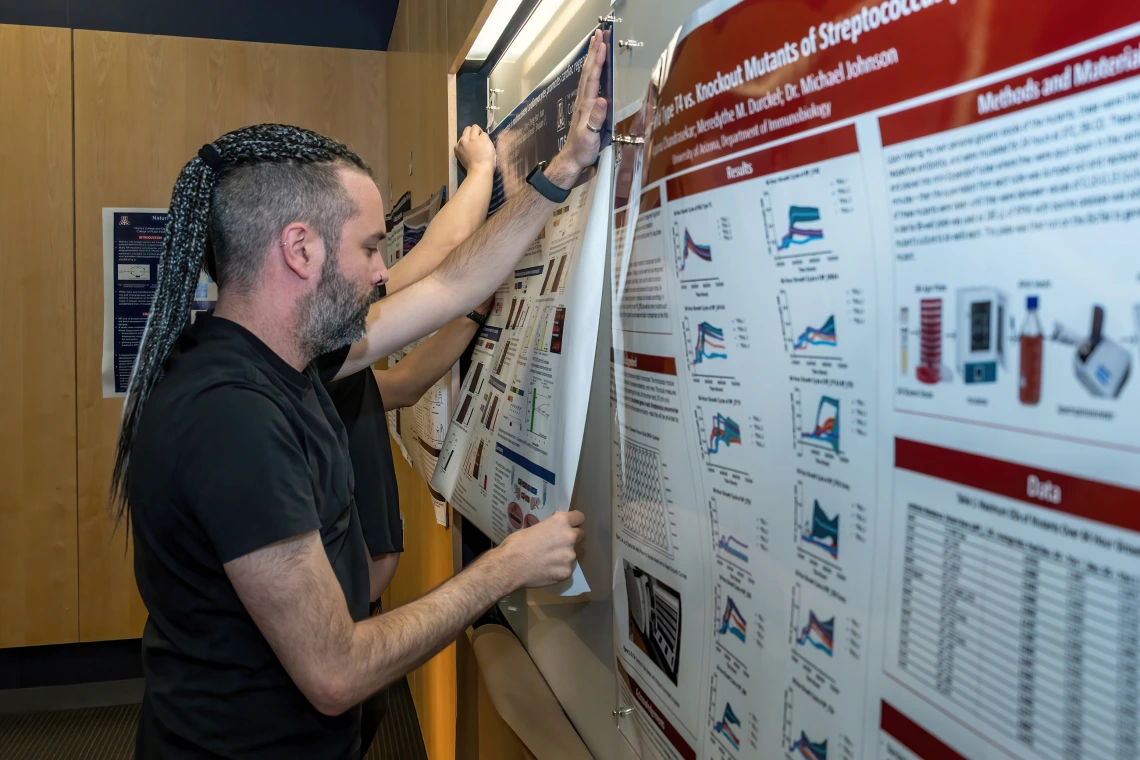 [Ivan Menendez Montes, PhD, a researcher in the lab of Cardiology chief and Sarver Heart Center director Hesham Sadek, MD, PhD, pins up his poster for display in the SOAR in the DOM Forum, April 24, at the BIO5 Institute.]