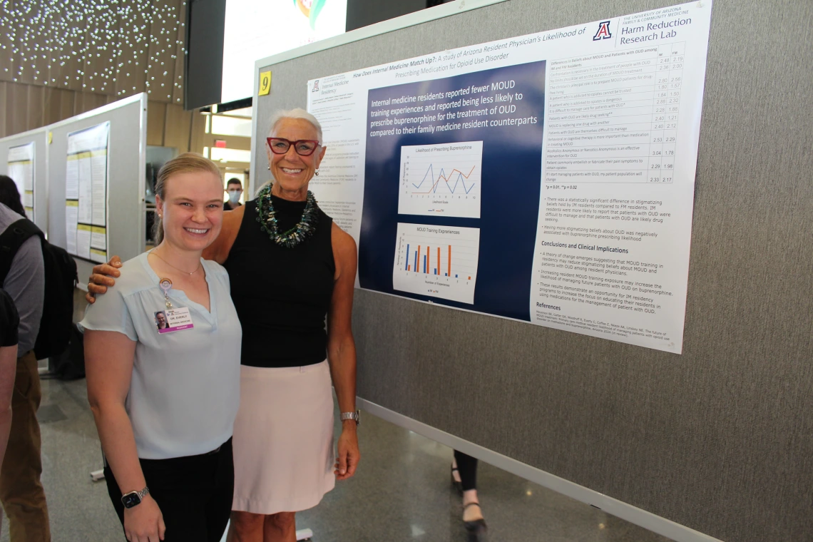 [PGY-1 IM resident Cassandra Everly, MD, MPH, with one of her co-authors Beth Myerson, MDiv, PhD, founding director of the Department of Family & Community Medicine’s Harm Reduction Research Lab, next to their poster: “How Does IM Match Up? A study of Arizona resident physicians' likelihood of prescribing medication for Opioid Use Disorder.” The center was created in 2018 to improve opioid disorder diagnoses and reduce bloodborne illnesses like HIV and hepatitis. ]