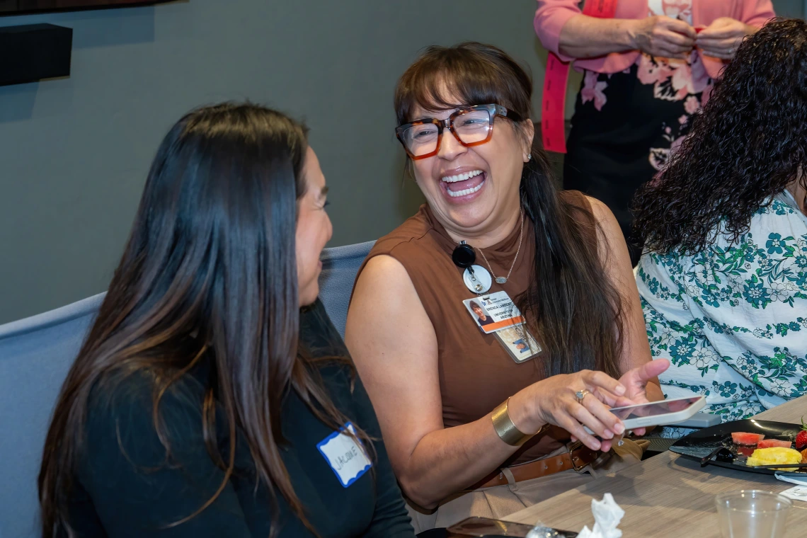 [Jacque Carrillo and Brenda Lambert, admins and fellowship coordinators in the Division of Pulmonary, Allergy, Critical Care & Sleep Medicine, share a laugh during the 2025 DOM Administrative Professionals Day breakfast]