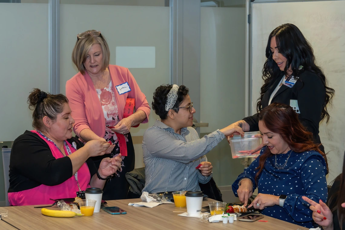[Gastroenterology’s Carmen Mendoza and DOM facilities coordinator Isabel Goodson-Montelongo accept raffle tickets from Cynthia Campas and Dominica Padilla at the 2025 DOM Administrative Professionals Day breakfast. Prizes were distributed later.]