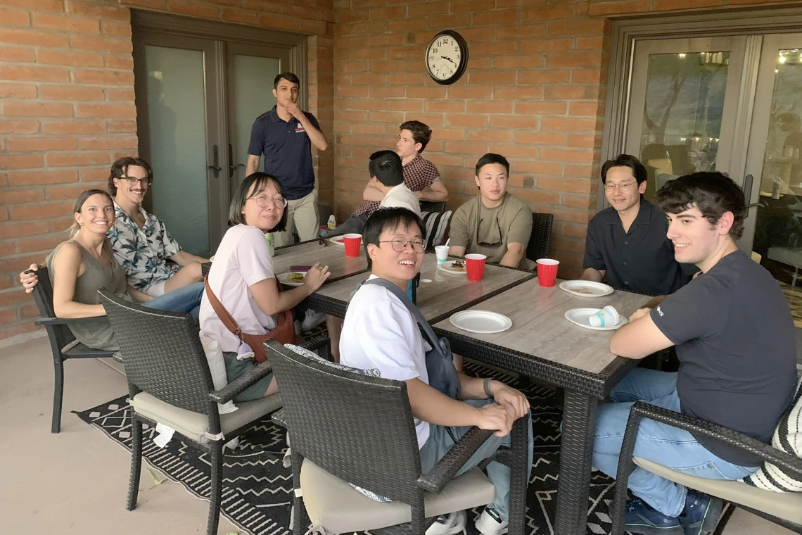 [After the Mount Lemmon trek, hikers relax in the shade back in Tucson, including (from left) Adrianna Diviero, MD,  her friend, Andres Sanchez, MD (standing), (unidentified - back of head to camera), Benjamin Maglajac, MD, (unidentified), Hyun Kim, MD, Chris Sallurday, DO, and (in the foreground, center) Justin Le, MD, and Laura Tran, MD, with lunch and cold beverages.]
