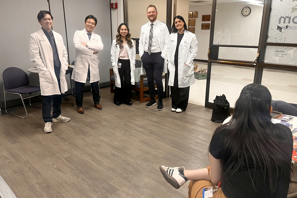 [In their white coats (from left), new Internal Medicine interns Tim Yu, MD, Shawn Wang, MD, Nellie Tolliver, MD, Cooper Stateler, MD, and Sheyda Mesgarzadeh, MD, wait their turn for profile photos to be shot at the UAHS BioCommunications photography studio on the College of Medicine – Tucson’s third floor.]