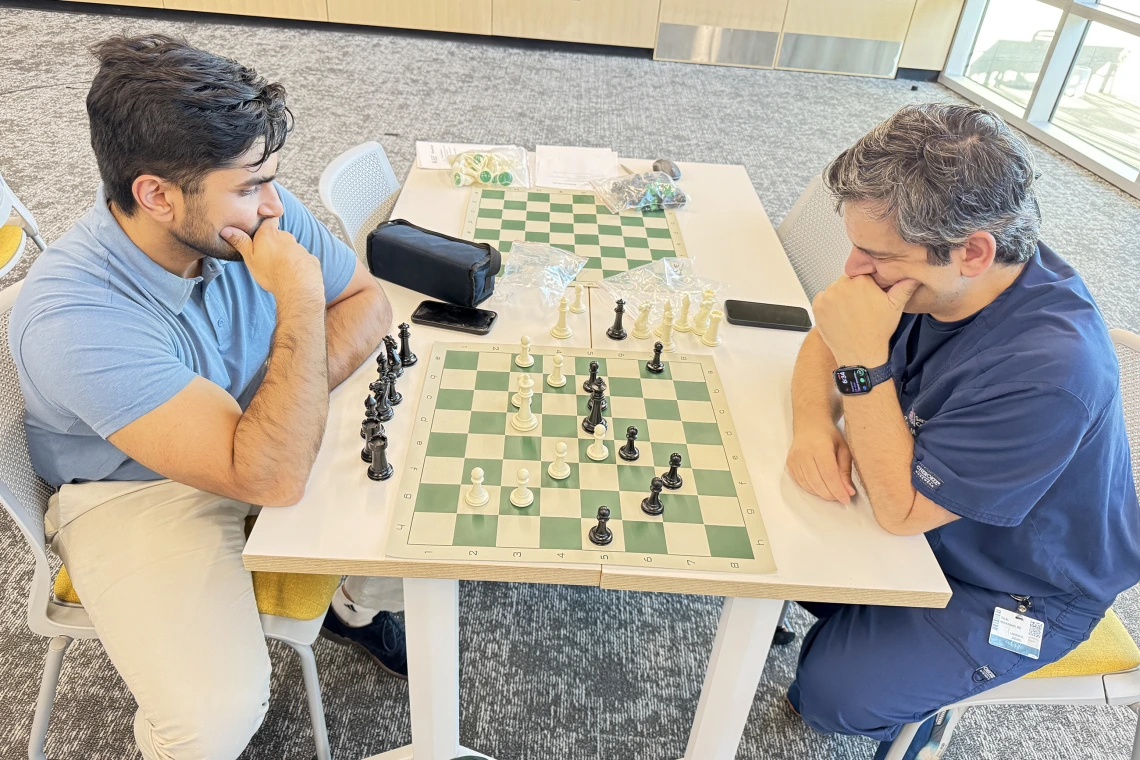 [The Division of Cardiology’s Talal Moukabary, MD (right), and Class of 2026 COM-T medical student Rohan Mittal give hard thought to each other’s next play as their match progresses: “I really appreciate all the work done to make this happen. I hope we make it a monthly event,” Dr. Moukabary said.]