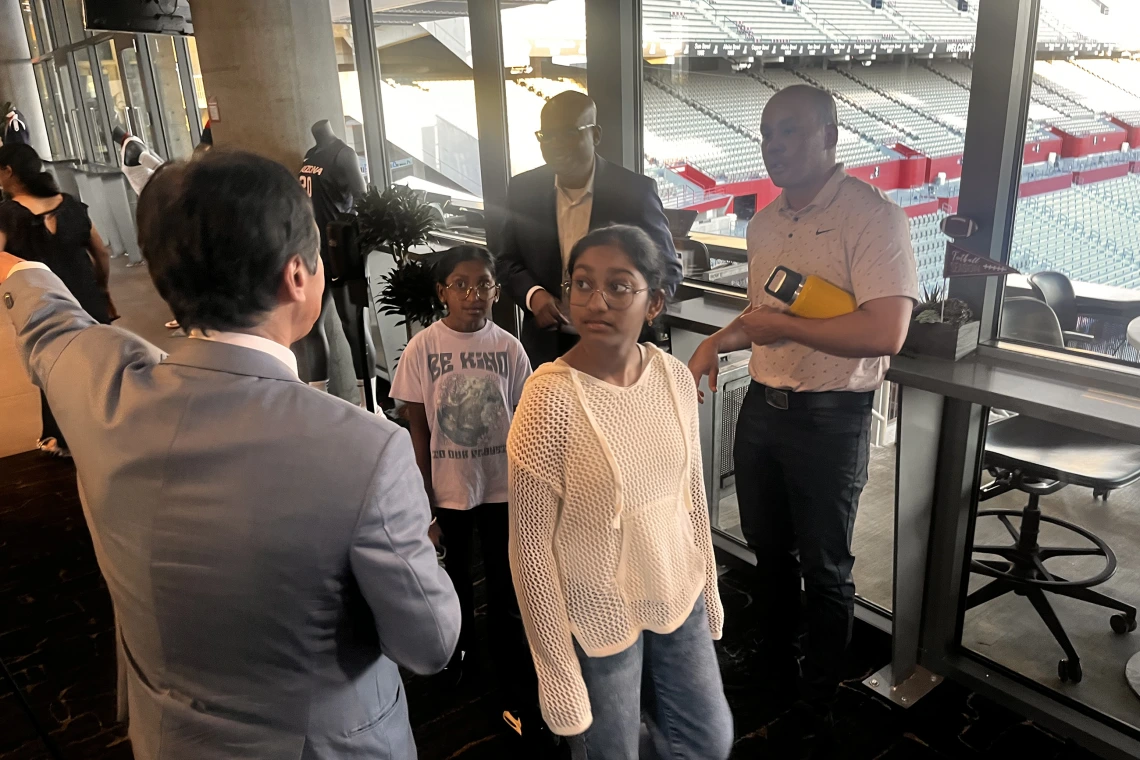 [DOM Chair Jim Liao, MD, directs people looking out over the Arizona Wildcats football field – including Scott Hall (right) and Venki Ariyamuthu, MD – to where dinner is being served.]