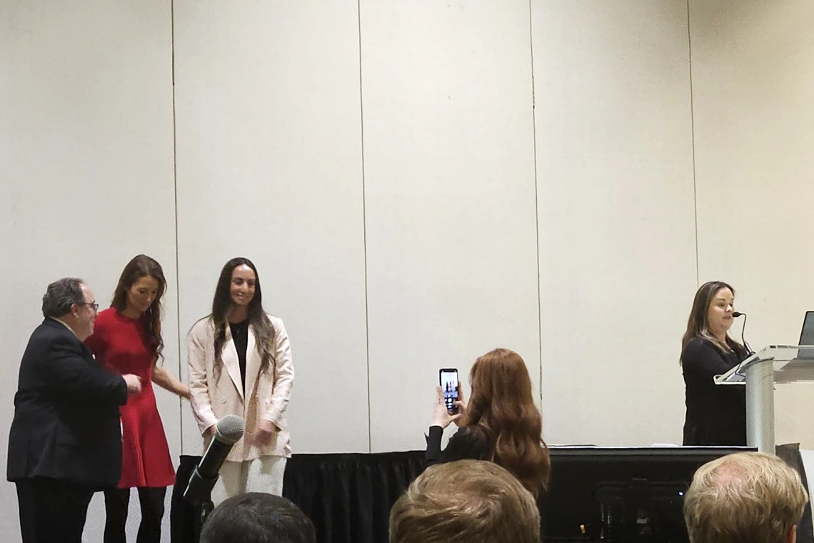 [Resident of the Year Emily Tishkoff, DO (3rd from left), a second-year resident from the DOM’s Internal Medicine Residency Program – Tucson, smiles as a photo is taken of her, with ACP Arizona Chapter governor Allan Markus, MD, MS, MBA, FACP, and 2025 ACP-AZ Scientific Meeting chair Krystal Renszel, DO, FACP, to her left and the DOM’s Joy Bulger-Beck, MD, FACP, ACP-AZ Awards Committee chair, extolling on Dr. Tishkoff to her right.]